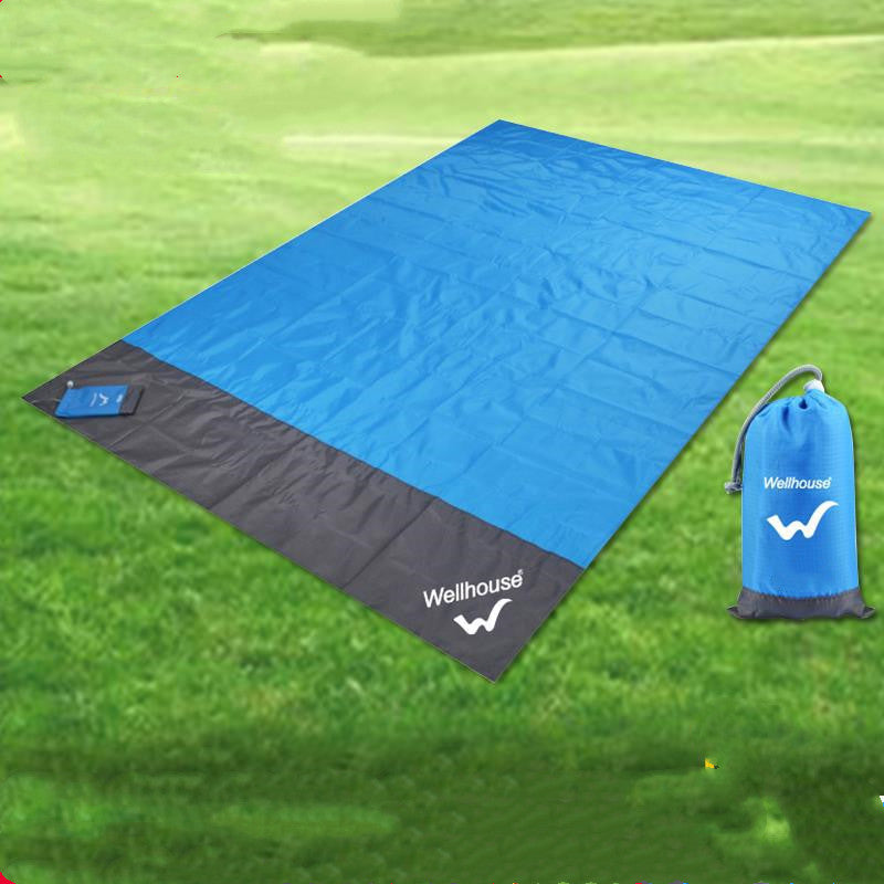 Waterproof blue and black camping mat with a bag on grass.