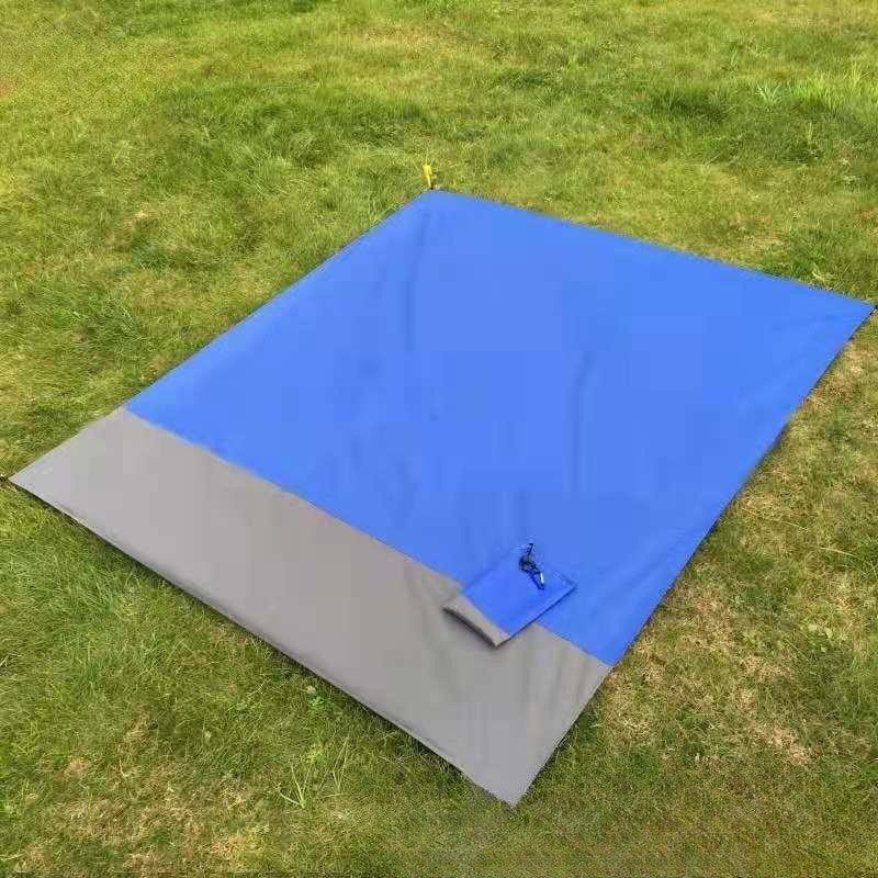 Blue and gray foldable beach mat on grass.