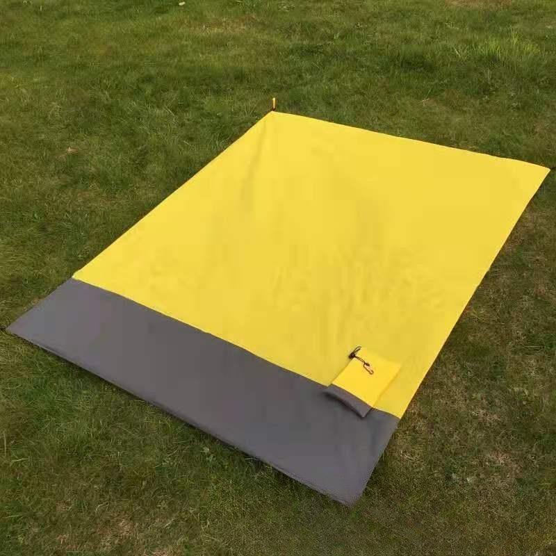 Fluorescent yellow and gray foldable beach mat on grass.