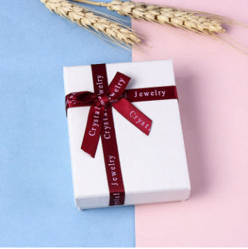 White gift box with a red ribbon on a split blue and pink background.