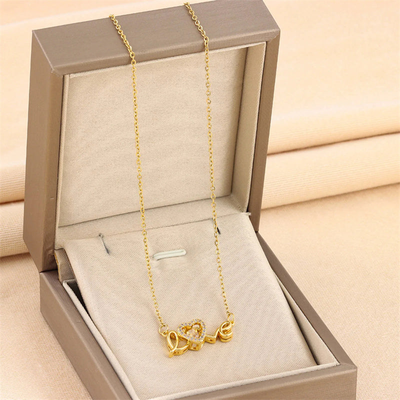 Gold necklace with heart-shaped charms in an open jewelry box on a beige background.