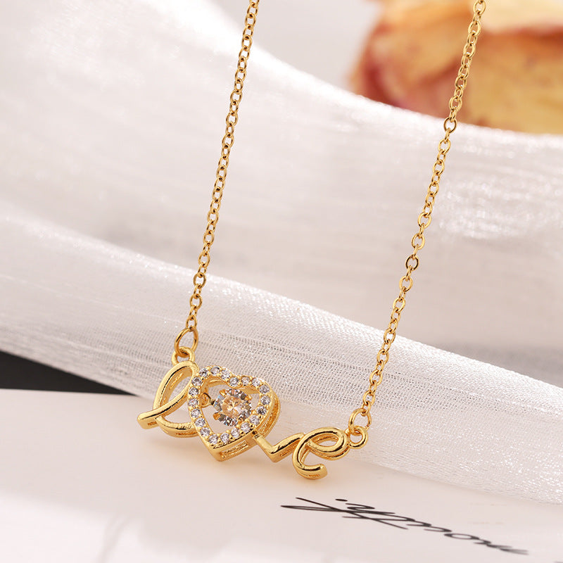 Gold necklace with «love» and heart-shaped pendant on a white surface.