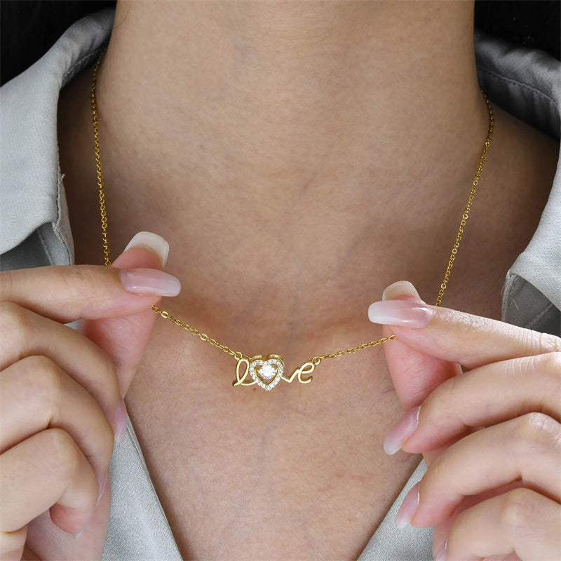 Gold necklace with a heart and «love» symbol worn by a women.
