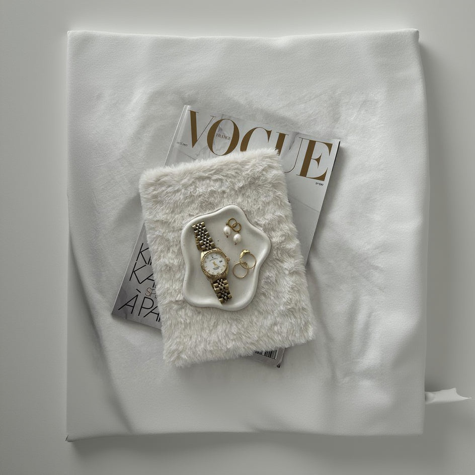 Jewelry set on a fluffy white surface with a «Vogue» magazine underneath.