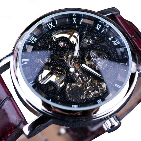 Close-up of a mechanical watch with a red strap and transparent face.