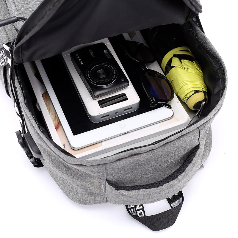 An open gray backpack containing a tablet, camera and umbrella on a white background.