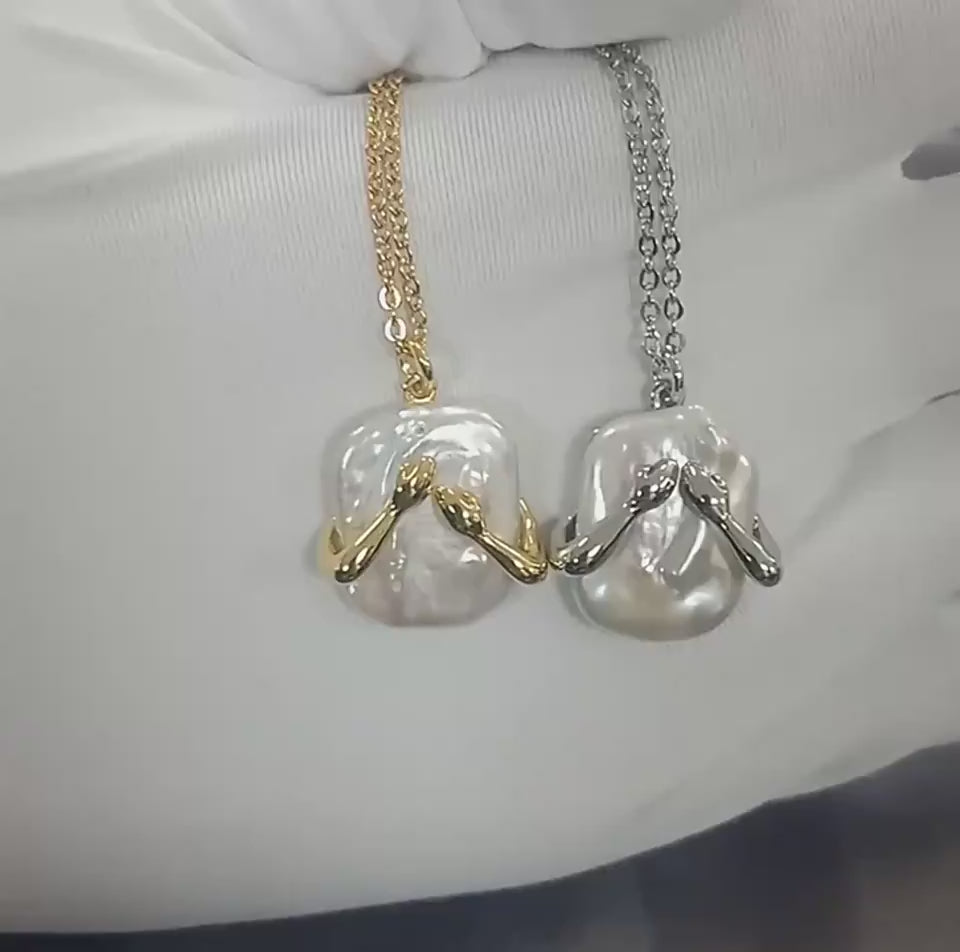 Video showing a white gloved hand presenting two necklaces in motion, featuring clear gemstone pendants with gold and silver chains.