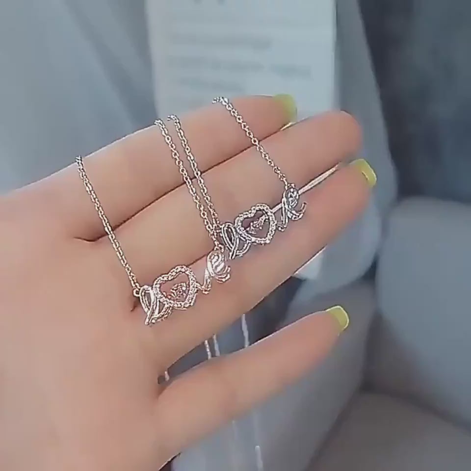 Video showing a women first holding a «Love» necklace in her hand, then transitioning to it worn on her neck.