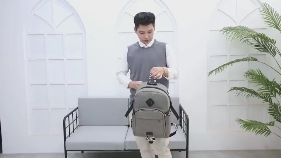 Video showing a boy trying on backpacks, turning to display each one in gray, black, blue and red, then taking items out of the gray bakpack and demonstrating the USB charging port.