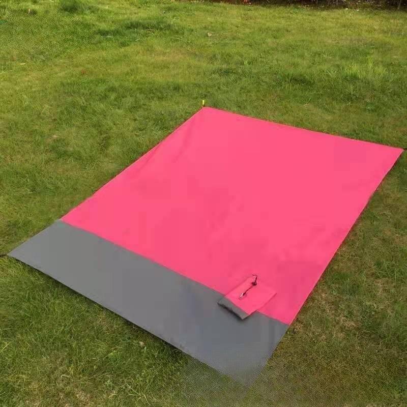 Rose red and gray foldable beach mat on grass.