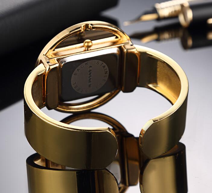 Women´s gold bracelet watch with brand logo on reflective surface.