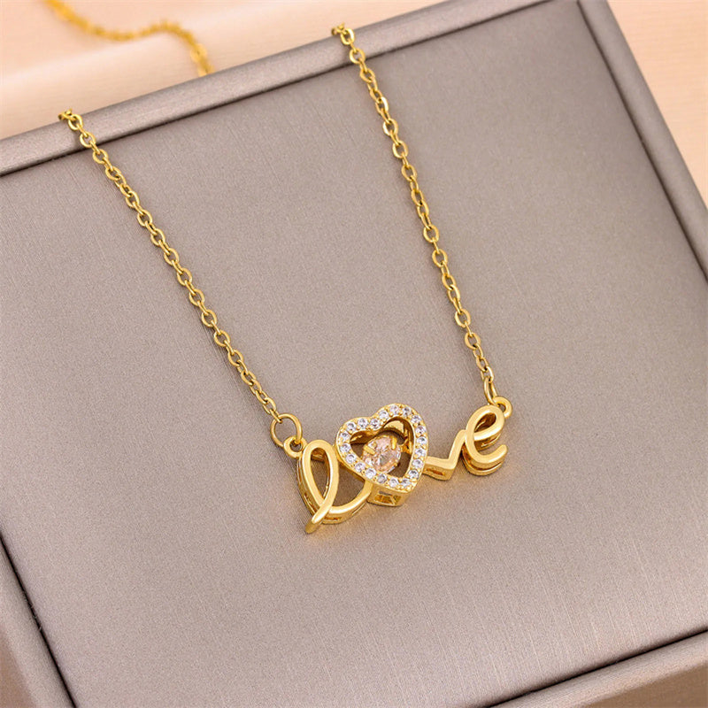 Gold necklace with «love» pendant on a gray surface.