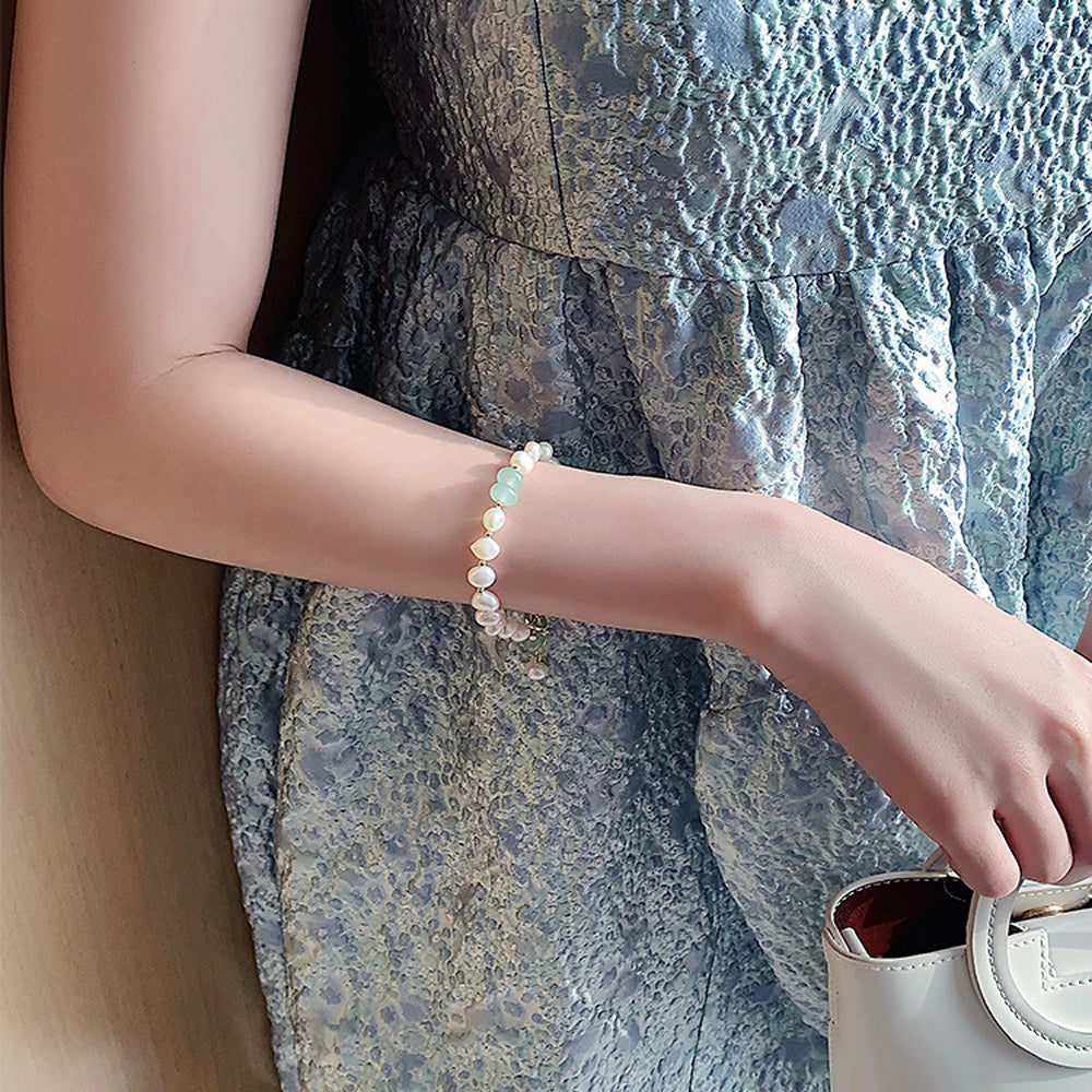 Women wearing a pearl bracelet with textured dress and handbag.