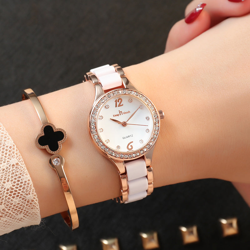 Rose gold women´s watch, white dial and bracelet with diamond-like accents on dark background.