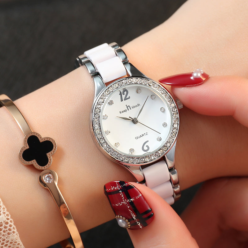 Silver women´s watch, white dial and bracelet with diamond-like accents on dark background.
